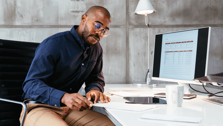 Commission management hero image, man sitting at desk reviewing paperwork