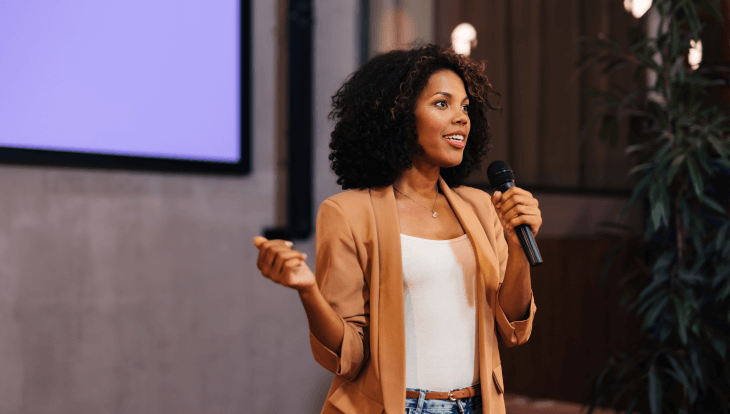 how to involve marketing in your SKO blog, image features a woman speaking in a microphone and presenting