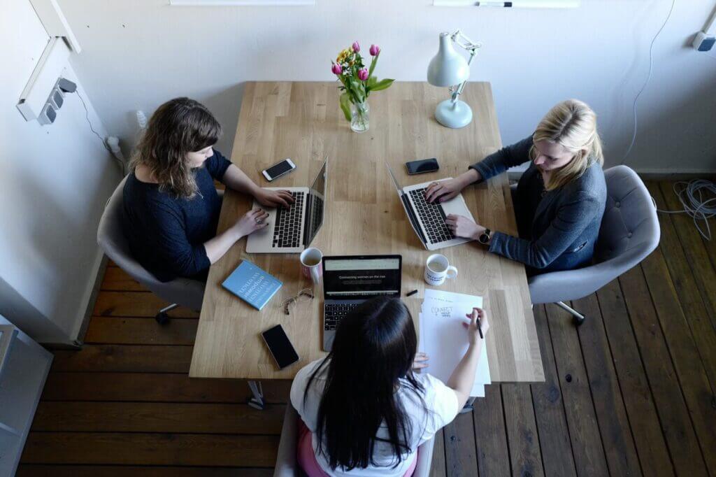 Overhead view of three women working on their lap tops at a table