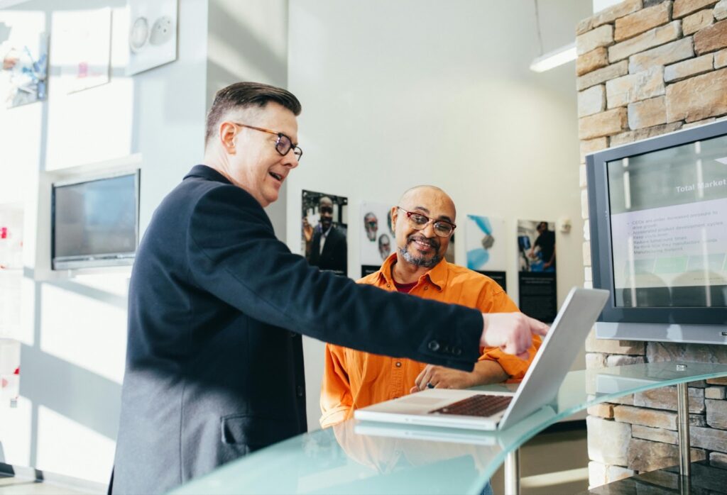 Two men talking over a work computer