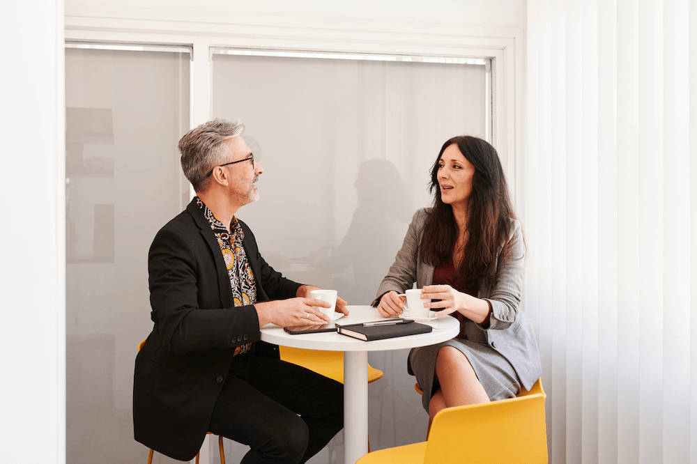 two people having a discussion at a work table. For blog "how and when to churn customers"